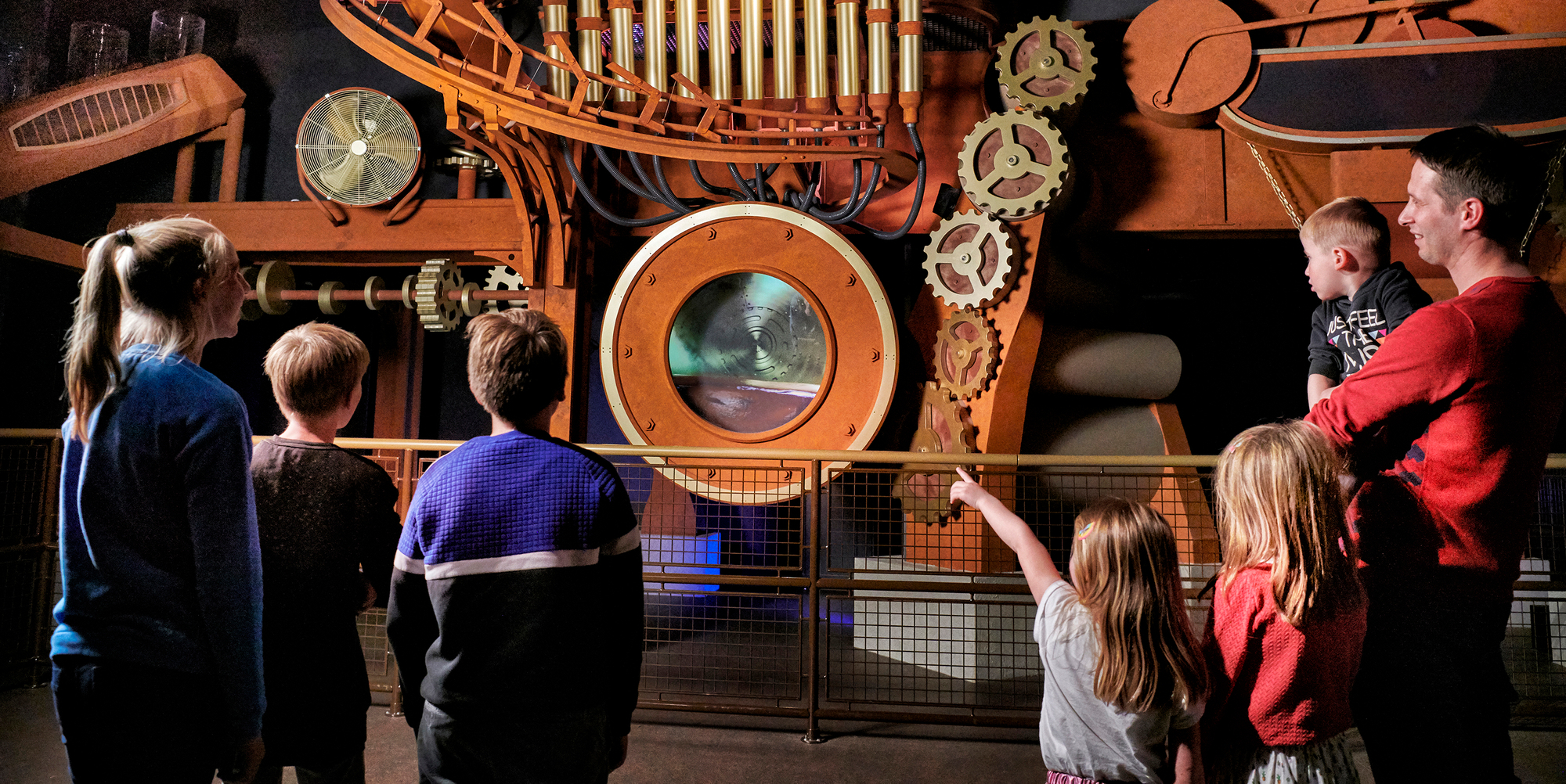 Verschillende mensen staan in het museum Chocolate Nation voor een oude, reusachtige machine. Verschillende mensen staan in het museum Chocolate Nation voor een oude, reusachtige machine.